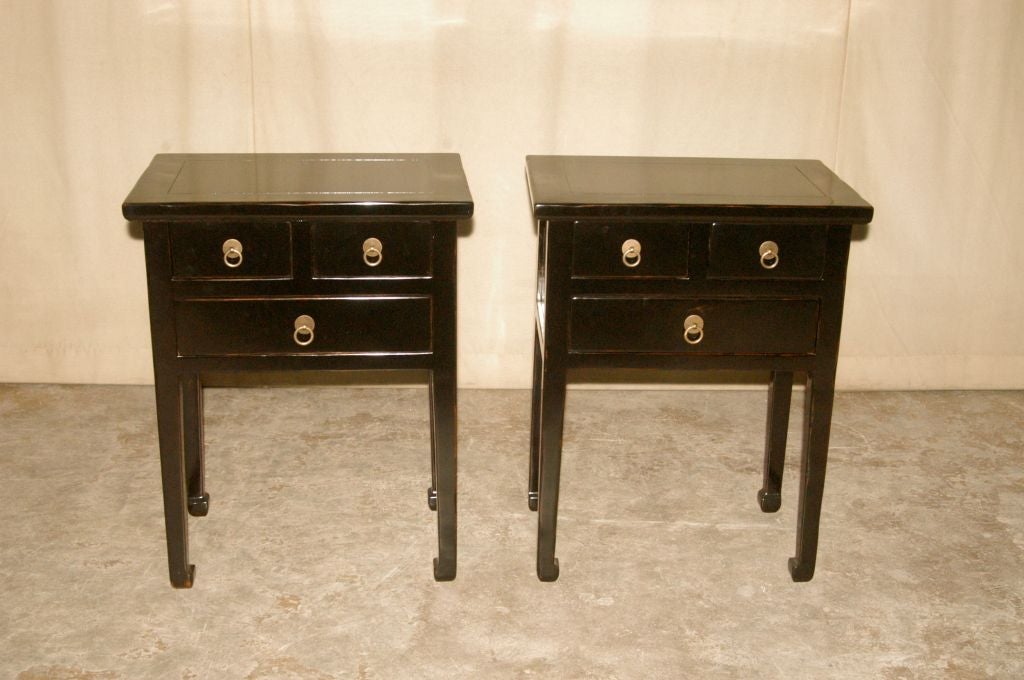 A pair of simple and elegant black lacquer end tables, three drawers with brass ring pulls, beautiful color, form and lines.