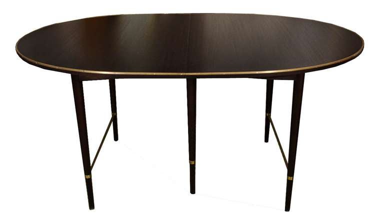 Paul McCobb black lacquered mahogany oval extension table Ca.1960 for Directional.Table has a nice solid brass trim that outlines the table top edge along with solid brass stretchers that join the legs. Table has 2-11