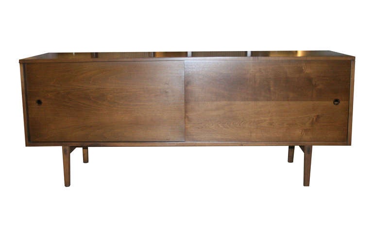 Paul McCobb Planner Group Low Profile Sliding Door Console.Solid maple construction finished in a medium walnut tone.2 sliding doors reveal 2 adjustable shelves on the interior.Fully restored inside and out.