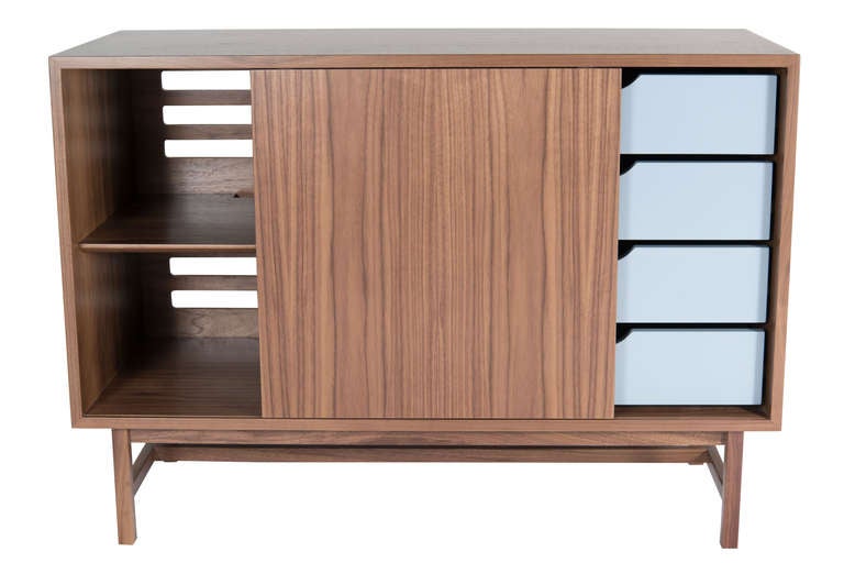 Mn Originals single sliding door walnut console. American walnut construction throughout detailed with colored lacquered tray style solid walnut drawers. Asymmetrical configuration of left and right sides providing both drawer and adjustable shelf