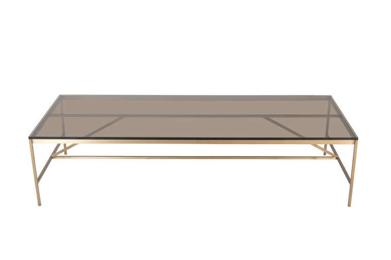Thin profile brass frame cocktail table with bronze glass top. Half inch square stock brass frame supports half inch bronze glass top.

Custom orders have a lead time of 8-10 weeks FOB NYC. Lead time contingent upon selection of finishes, approval