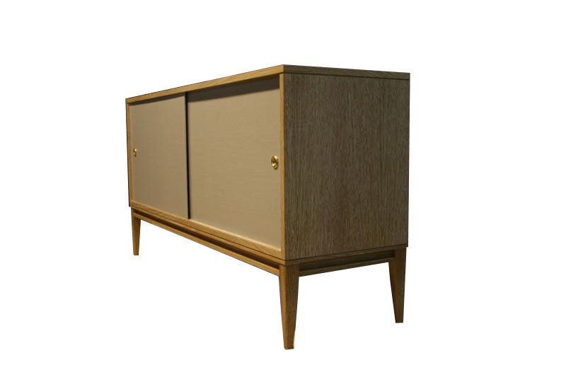 Mn Originals cerused oak console on solid tapered leg base with belgium linen sliding doors detailed with solid brass finger pull hardware.Interior has adjustable shelving and cerused finish to match exterior.

Custom orders have a lead time of