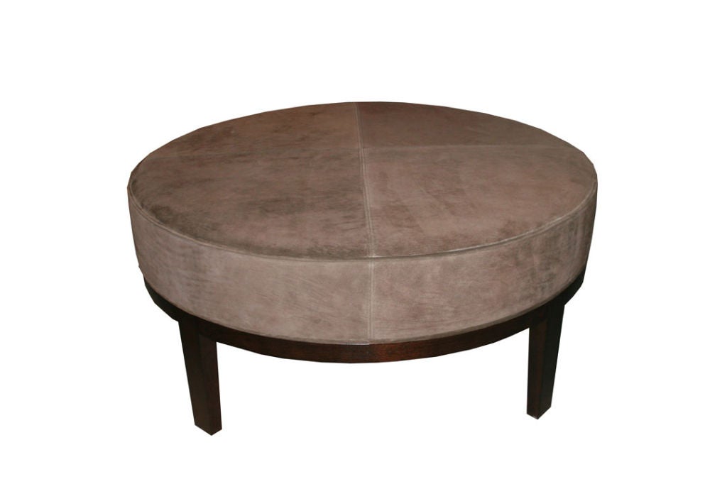 Solid walnut four-leg round ottoman with tight quarted upholstery. Double saddle stitch detailing top with self welt edging tight to a solid walnut tapered leg base.

COM requirements: 4 yards. 
5% up-charge for contrasting fabrics and or