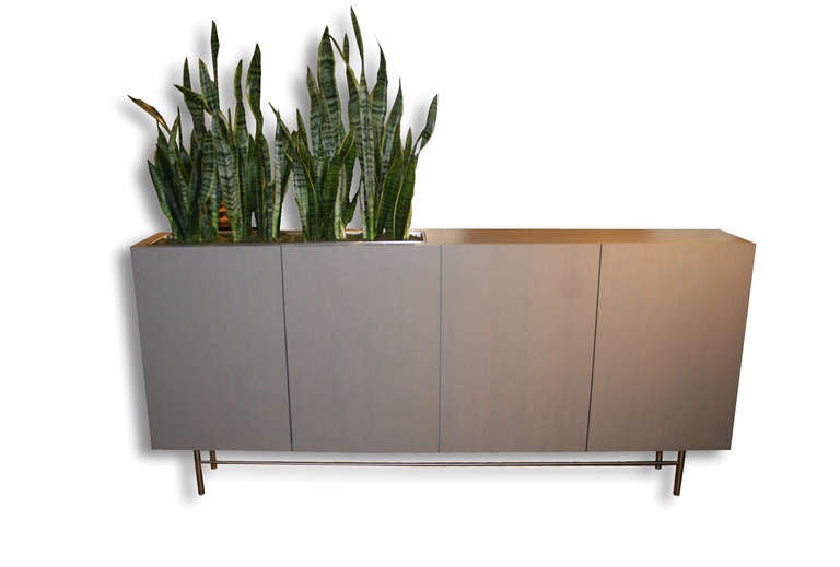 Rift oak thin profile planter console on stainless steel base. Four door consoles coupled with inset stainless steel planter box. Adjustable shelf interior and finished back panel make this piece perfect for a free floating room divider style