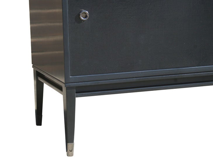Mn Originals lacquered console with lacquered linen sliding doors detailed with black nickel finger pull detailing. Solid hardwood base finished with black nickel sabots. Interior adjustable shelving with fixed center support.
Sabots shown not