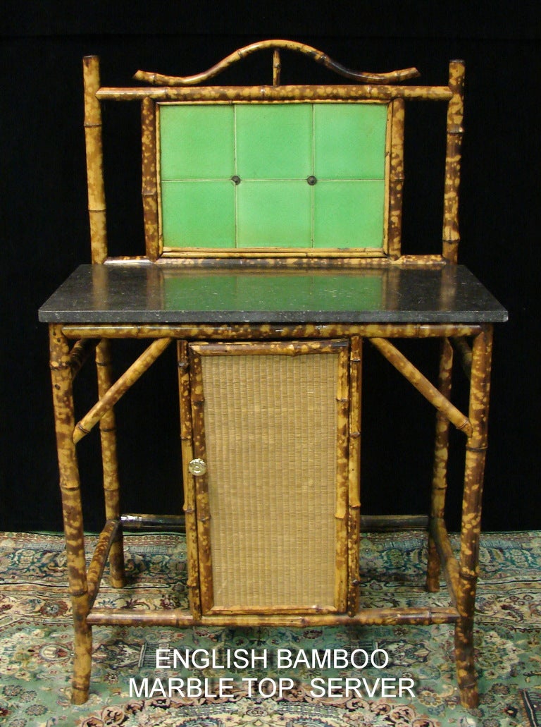 A Lovely 19 th century English Bamboo and Marble top Server. There are six Johnson and Johnson tiles on the back splash, the bamboo is in wonderful condition, one opening door with a cane panel and brass pull. The measurement from the floor to the