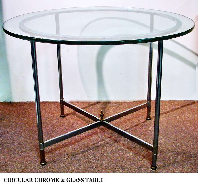 Polished steel and glass dining table or center table. Clean directoire lines of polished steel. The feet have brass trim. Center finial, one half inch thick glass, makes this a very sturdy piece. Seats four comfortably.