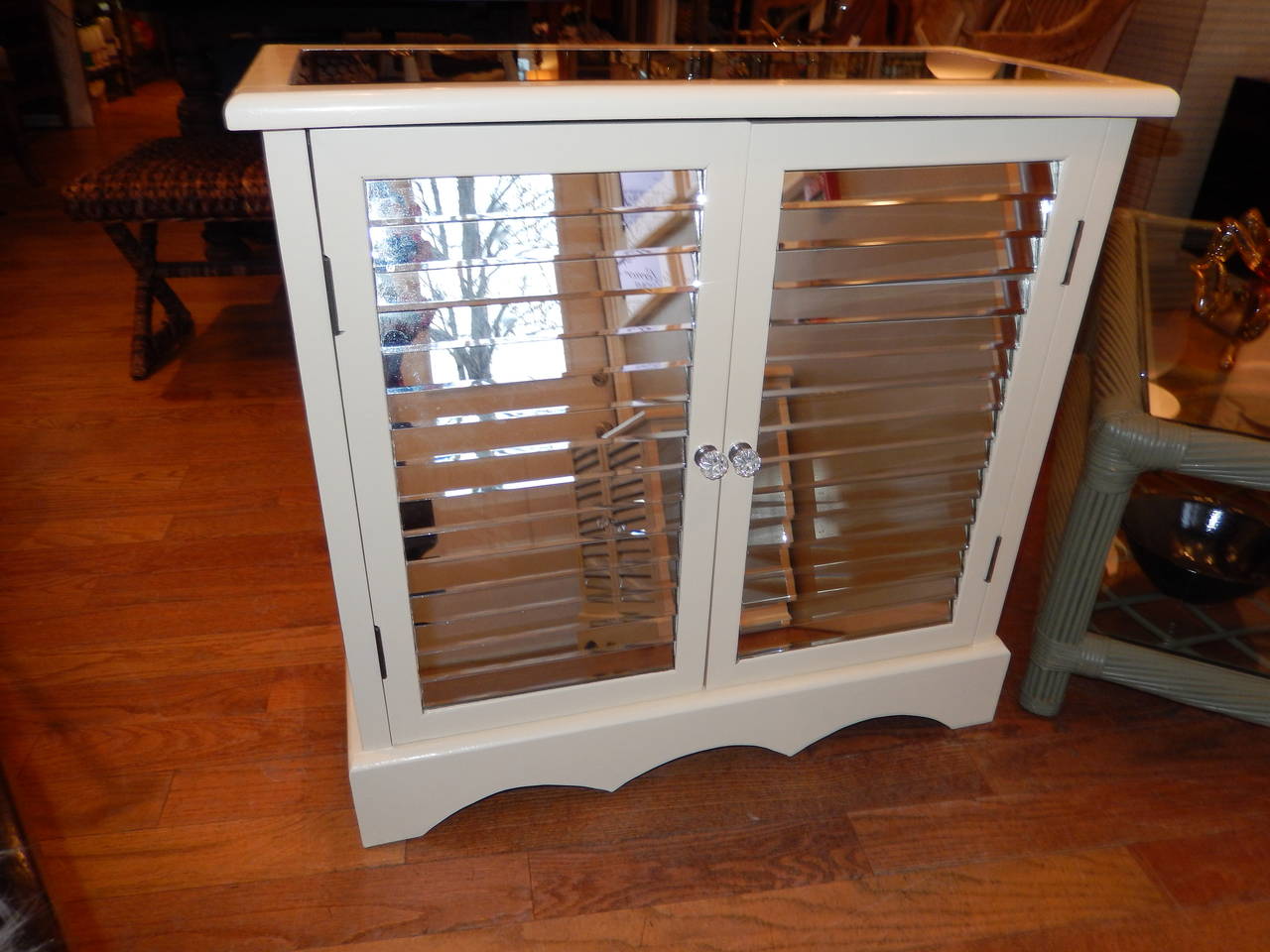 Pair of attractive painted (creamy ivory) mirrored side cabinets or cupboards with louvered doors.
The louvers are fixed so they will not move. The tops and sides are also mirrored. Doors open to good storage, with one shelf on the middle left.