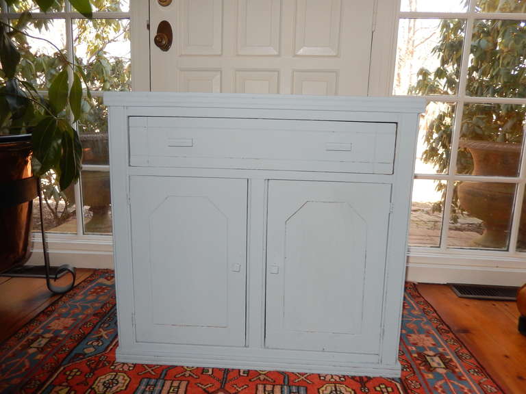 A two door and one drawer painted cabinet or cupboard. Recently painted in a dove grey/blue over walnut wood.
