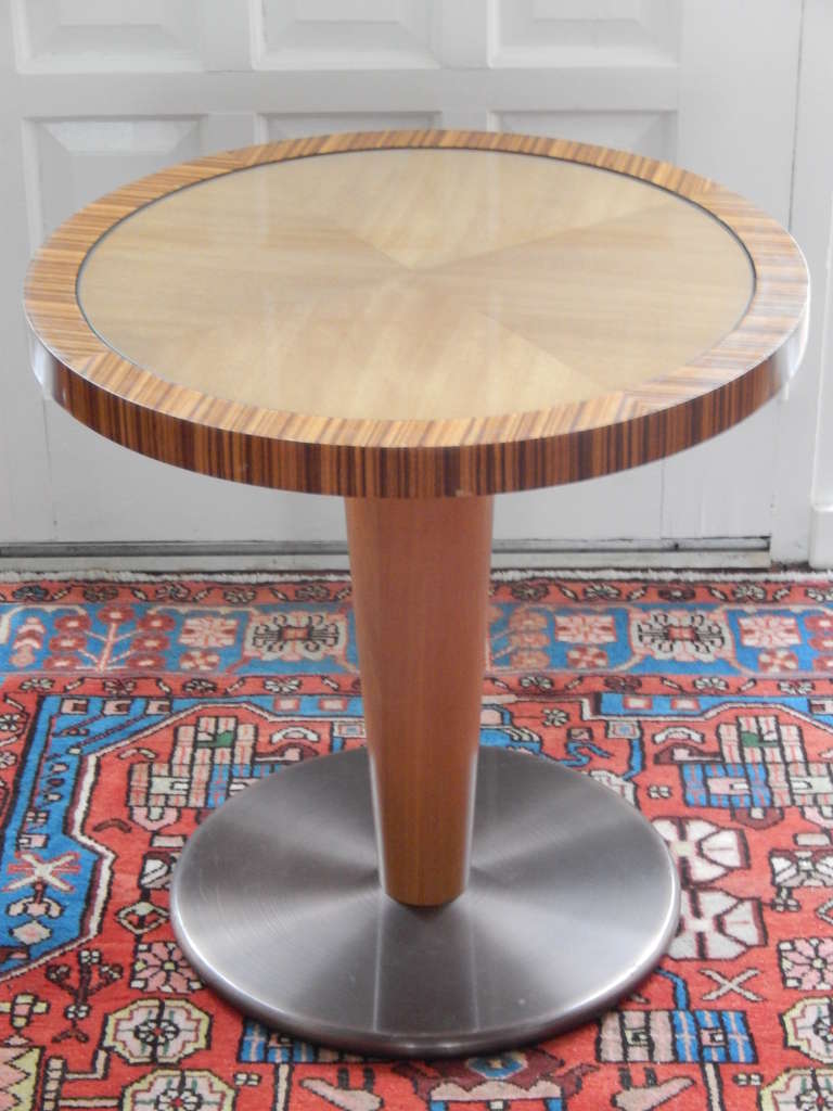 An interesting Mid-Century pedestal form occasional table. The base has a brushed bronze finish over steel, with a maple wood pedestal. Zebra wood around perimeter and light mahogany wood under the glass (top)