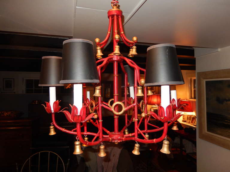A lovely Chinese Chippendale style bell drop chandelier. The gilt bells are all made of wood, the frame is metal (tole) with an oriental red lacquer finish.
Tulip form cups hold six white candle holders with six black and gold underlay shades. The