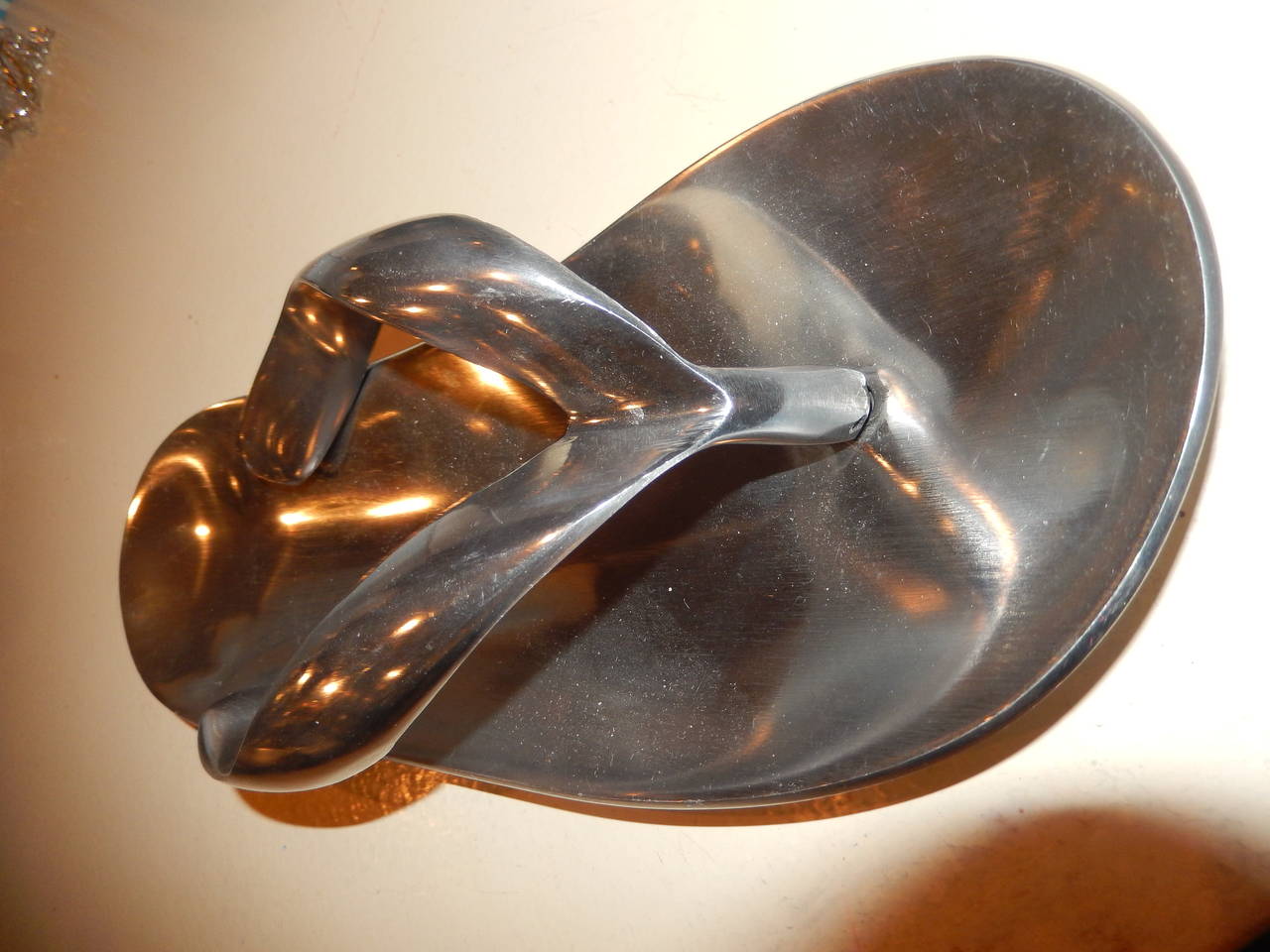 An artisan sculptural chrome flip flop, used as ashtray or paper weight.