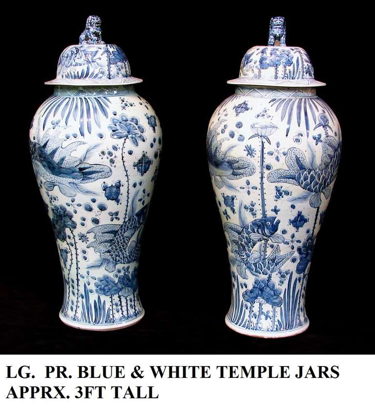 A striking pair of Chinese hand decorated blue and white Temple Jars.
Beneath  the ocean scenes of fish, water lilies and plants. Removable lids with well-detailed foo dogs in center top.