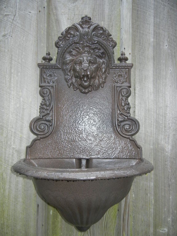 A cast iron water fountain or planter, showing excellent detail, especially on the lion head, powder coated bronze finish for out doors or in.