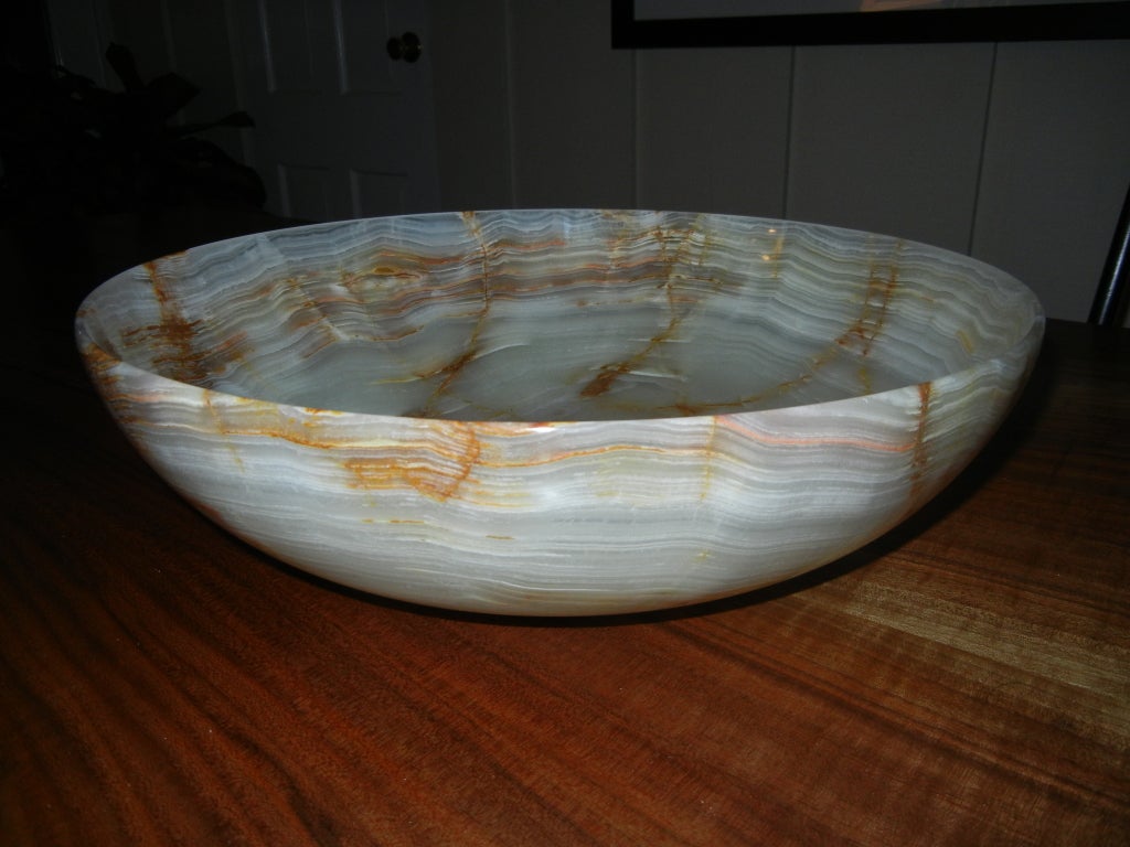 A wonderful center piece for any table,this large hand crafted onyx bowl,translucent in the light with streaks of amber and gold.