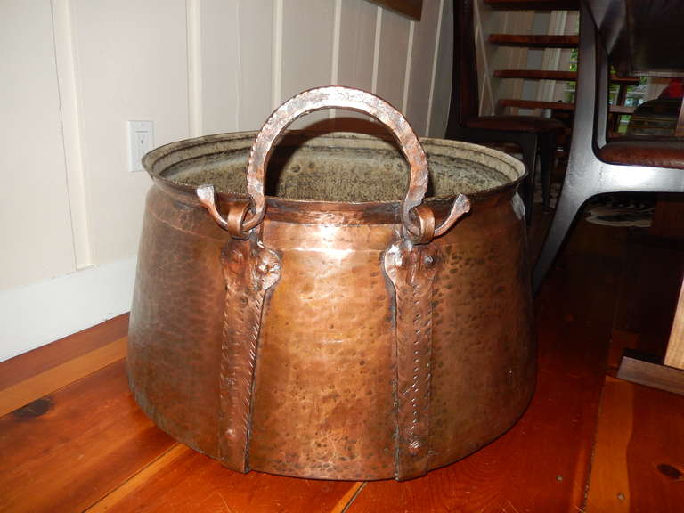 An antique English over sized  hand hammered copper, brass and iron cauldron.Large iron handles,great for firewood or plants.Christmas trees.