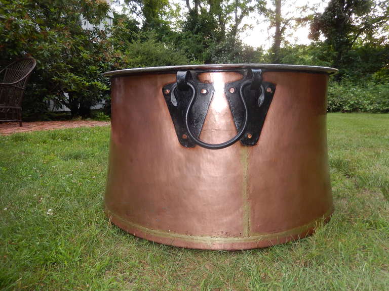A rare find in this extraordinarily massive copper cauldron, large enough to accommodate four people, all hand-forged, with a plated interior (for cooking use). Brass welding, blackened hand-forged hardware and handmade copper rivets with two