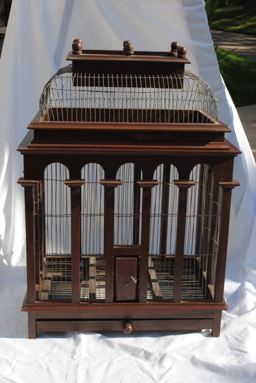 An English 1880-1890s birdcage with a convex curve domed roof (lifts off for easy access), arched apertures with capitals, six finials and a tin tray/drawer. All wooden parts and wires are intact, no rusting and very sturdy.