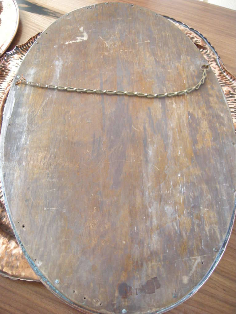 A 1890-1910 Arts & Crafts English hammered copper mirror, wood backed with original hanging chain.