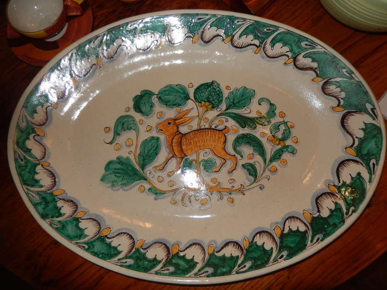A large ceramic oval shaped platter, decorated with a large hare, centered in the middle with vines and leaves. The platter is food safe, but can also be hung on the wall (wire in place).