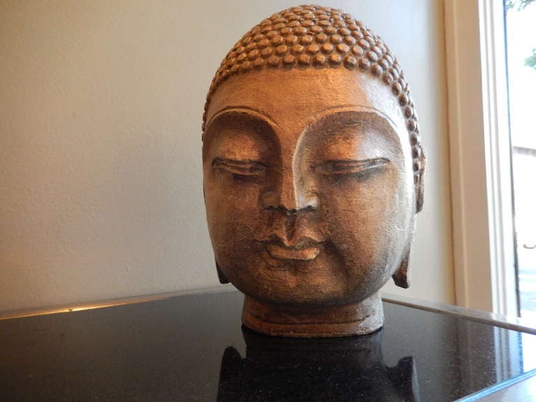 A late 19thc Indonesian hand carved stone Buddha Head. The face has an antique light golden warm glow.