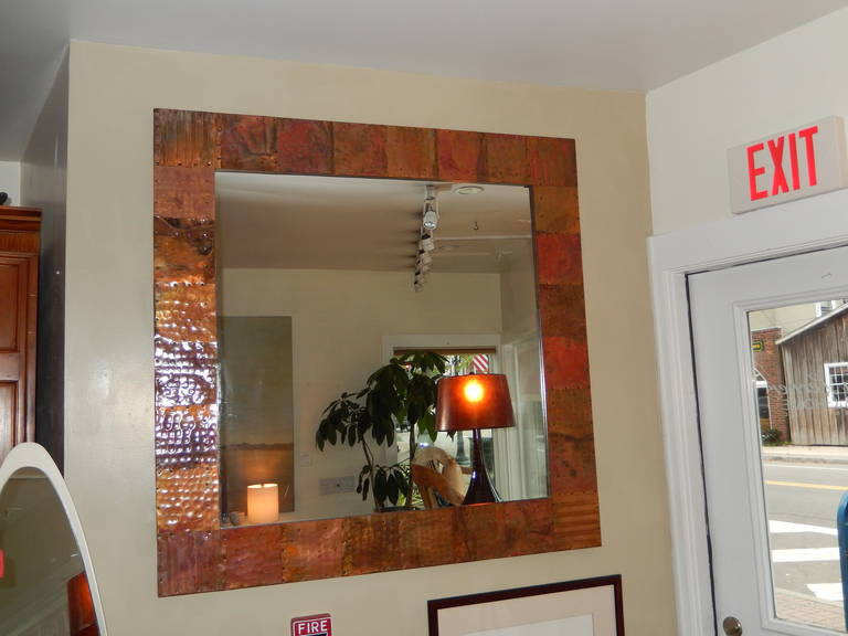 A large hammered copper Arts & Crafts style, mirror from England, cut to appear as copper tiles.