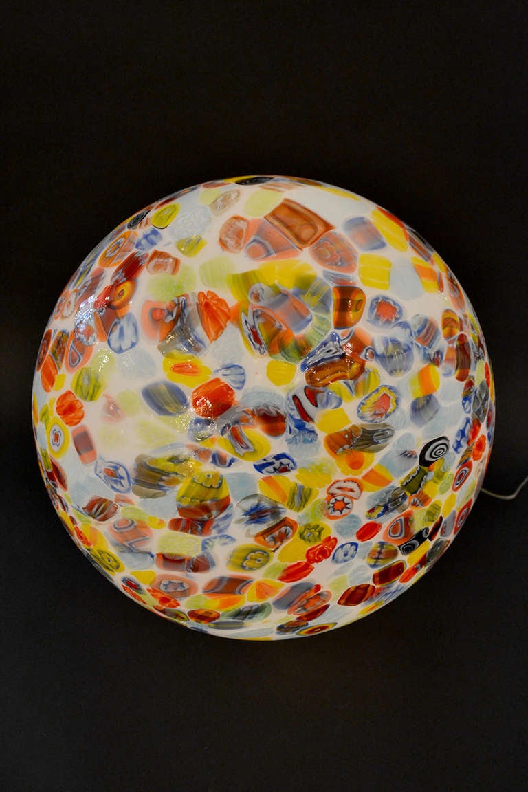 A vibrant and colorful millefiori globe lamp. The shade is comprised of a multitude of colors that swirl and illuminate a playful palette.
