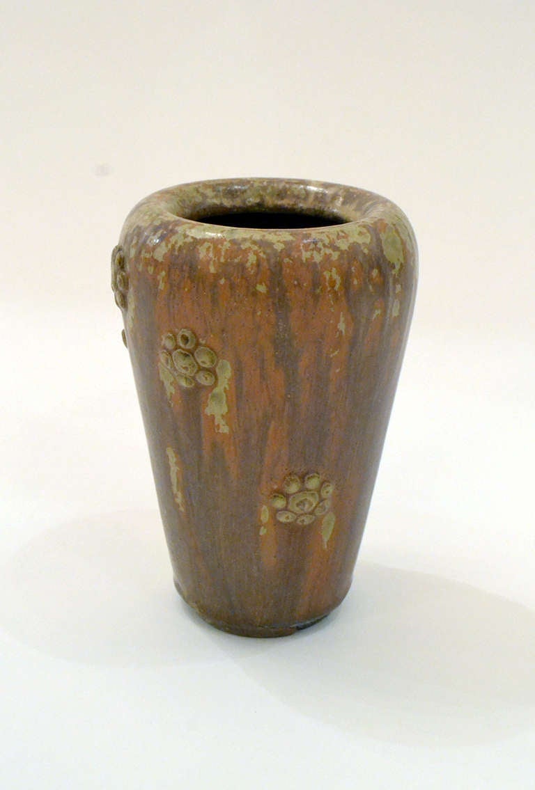 A wonderful and subtle bud vase by Arne Bang, the vase is adorned with small applied flowers and with a wonderful rusty orange glaze that crawls with hints of green.