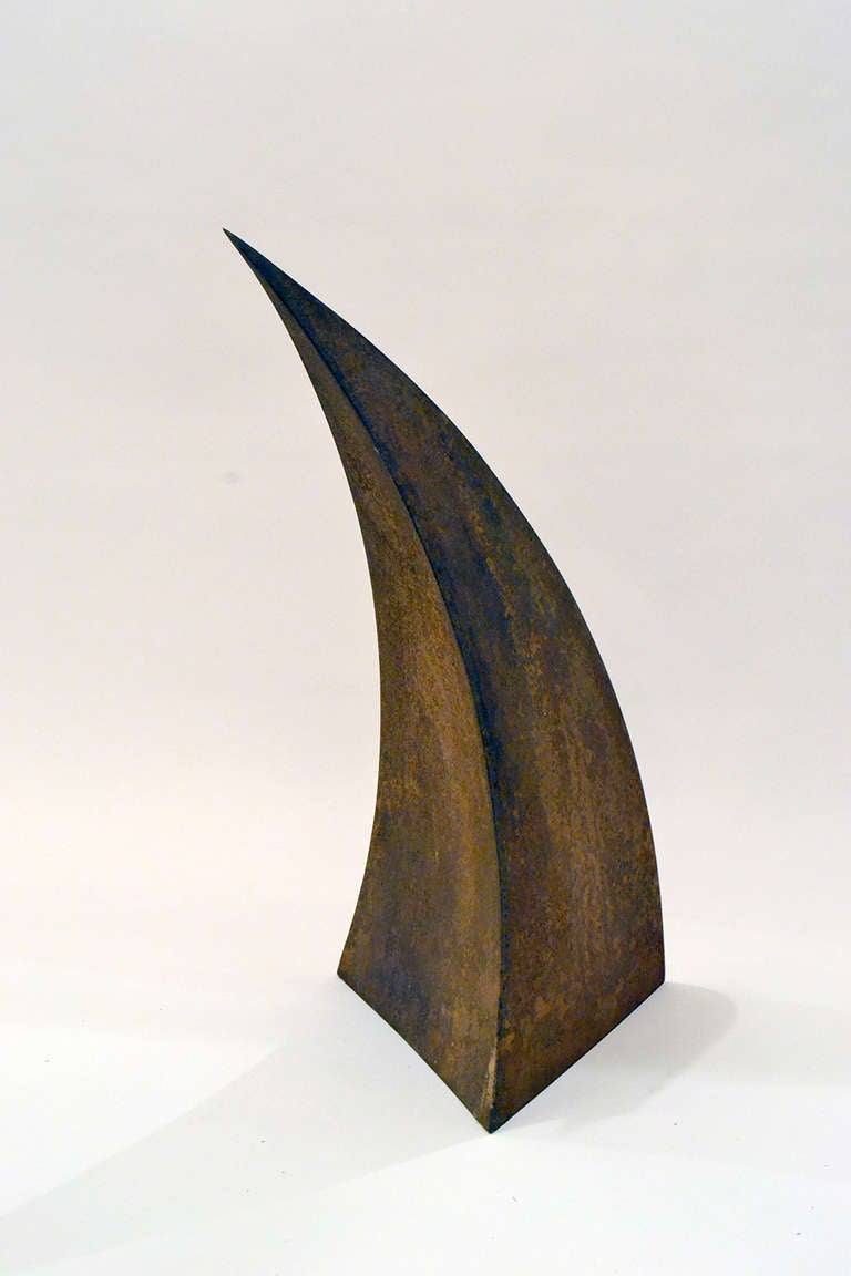 an abstract sculpture made of rusted, corroded steel. The shape is reminiscent of a cornucopia or thorn of metal.
