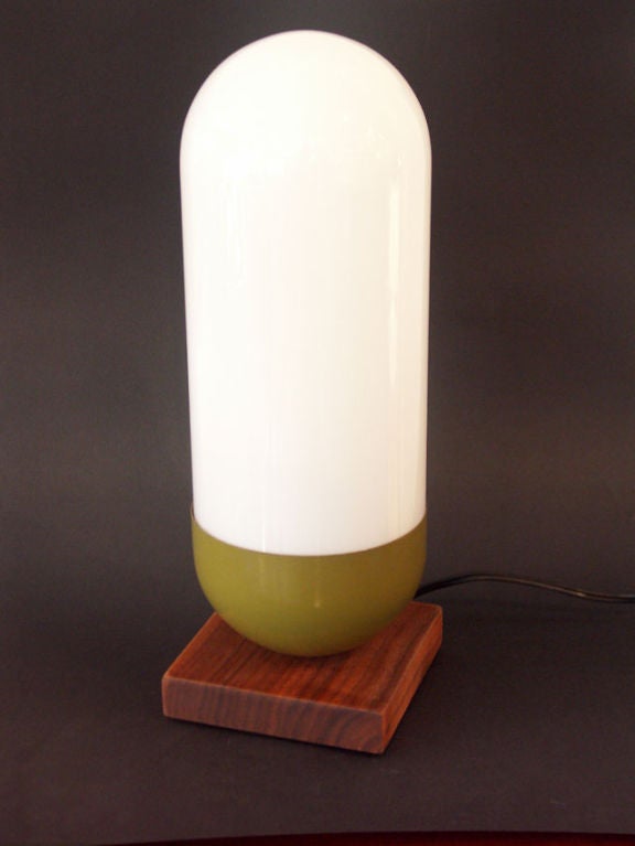 Capsule or pill form lamp by Design Line of El Segundo California. Solid walnut base with green enameled steel base, and white glass shade completing the capsule look.