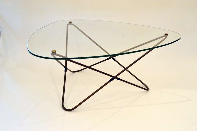A wonderful triangular Butterfly style coffee table from France by  Pierre Guariche. The glass top is mounted by brass caps that hold to the angular rod base.