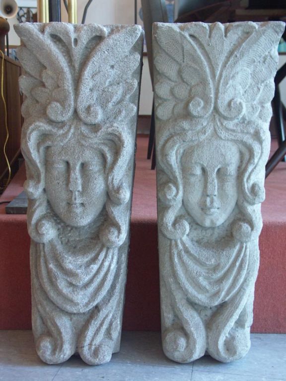 Beautiful pair of matching architectural limestone corbels depicting female faces. Each keystone is hand carved, with subtle differentiation between the pair, with highly stylized hair, flowing clothing and elaborate head dressings. Perfect as