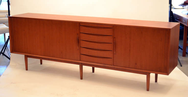 A wonderful teak credenza designed by Arne Vodder. The credenza is in typical fashion of Vodders's design with tambour doors and wonderfully sleek stacked drawers.