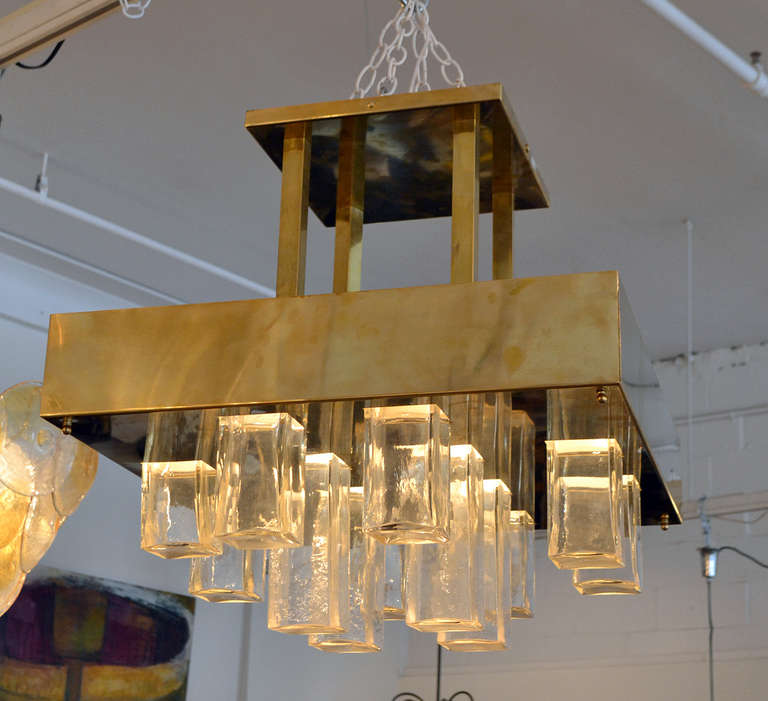 An elegant geometric ceiling fixture by Gaetano Sciolari, Italy. The fixture is comprised of 12 glass cubes that suspend from the square brass structure.