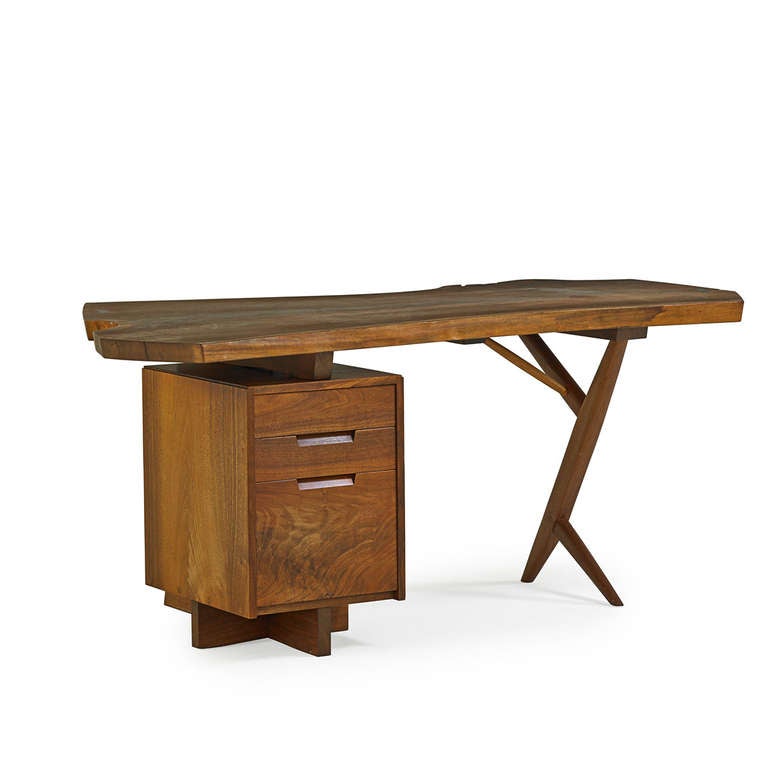 A beautiful and dramatic construction sets this desk apart from other works by George Nakashima. The stout pedestal features three drawers with inset handles, and is ingeniously designed so that it can be positioned on either the left or right hand