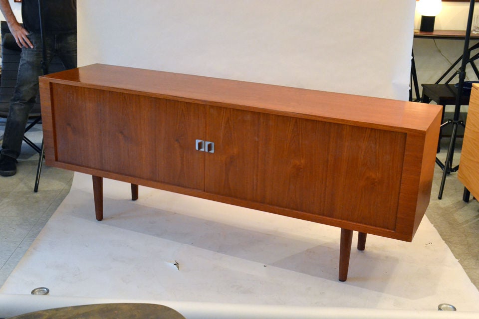 An amazingly simple design by Hans Wegner. The credenza is made of teak with solid teak tambour doors. There is an ample amount of storage including a set of sleeve drawers.