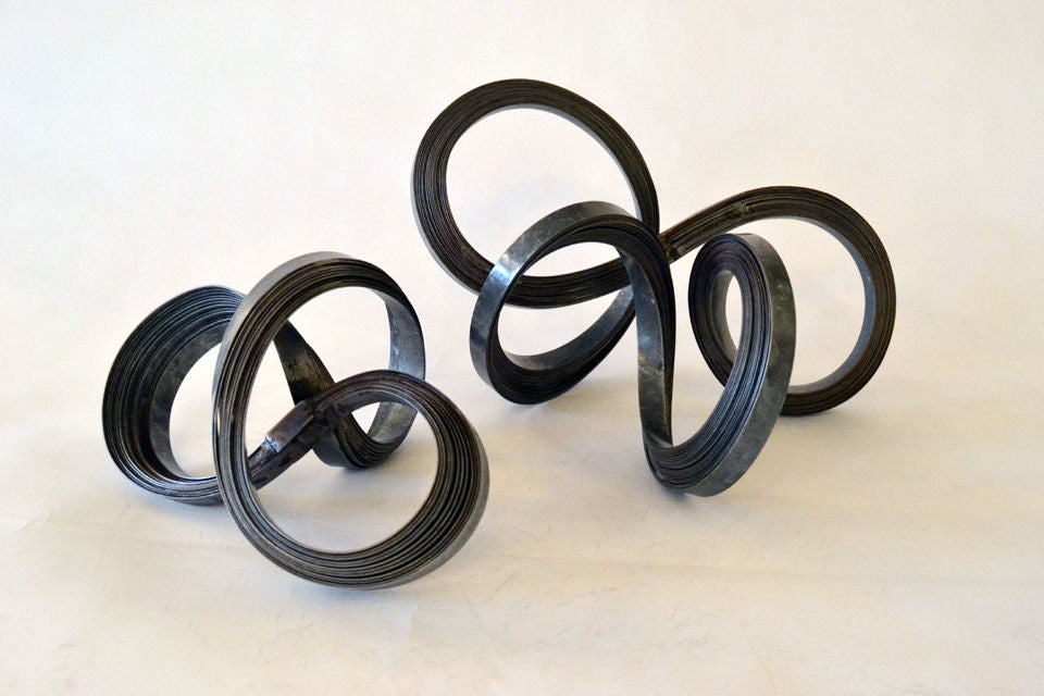 A unique pair of table top sculpture by Duayne Hatchett (b.1925). Galvalized steel bands are layered and twisted to conform into a curved and torched formation.<br />
price is $1,600 small, $2,400 for large