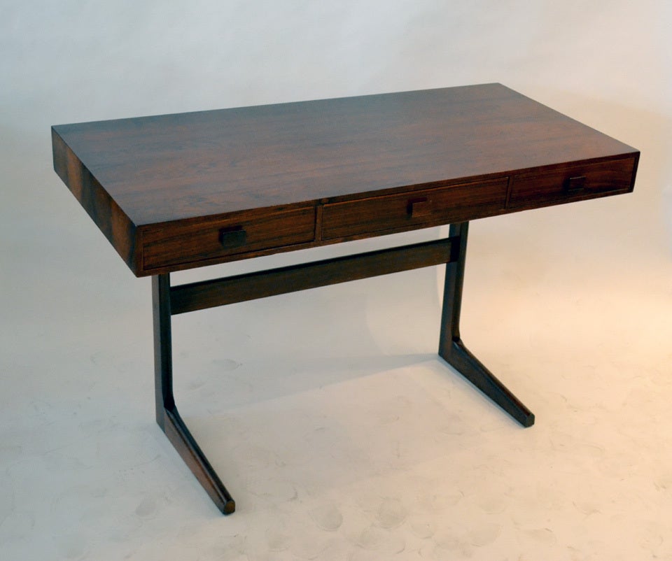 A wonderful Danish Modern desk in petite and compact scale. A great desk for extra and light task work. The desk sports three long drawers for storage and ample leg room.