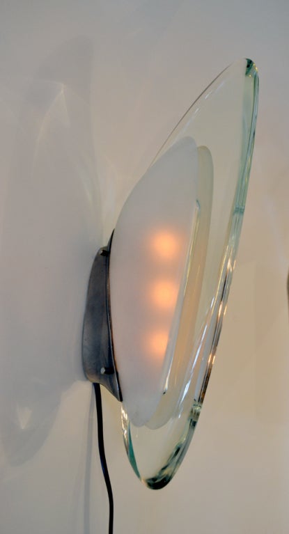 a rare and elegant pair of sconces by Fontana Arte, Italy. The sconces evoke a stylistic shape of fins. Each sconces supports three candelabra socket bulbs.