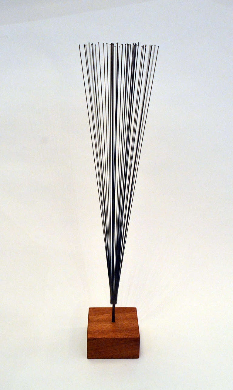 An early and experimental stainless steel sprig sculpture by Harry Bertoia (1915-1978). The piece is made of thin metal wires, beaded at their terminus, welded at the seam to a finishing nail and placed into a contemporary mahogany wood base. COA