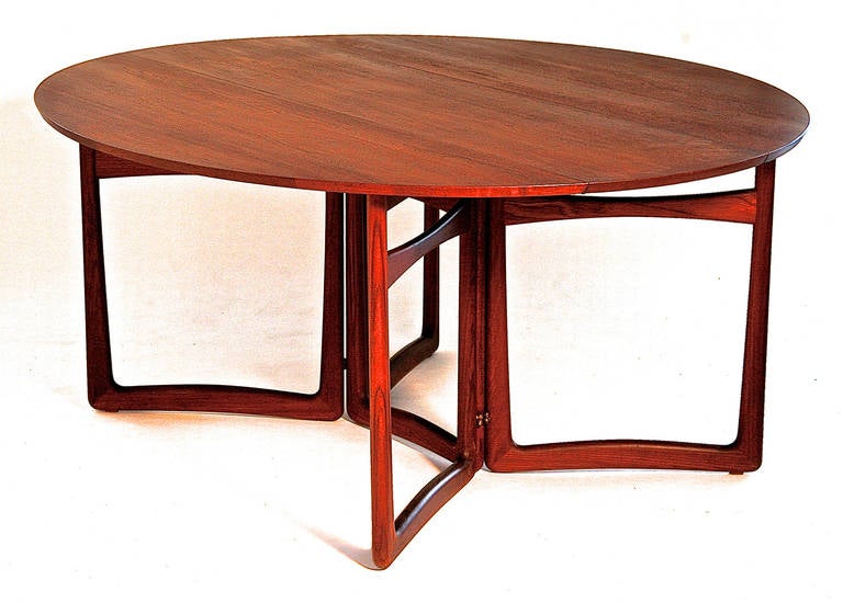 The beautifully sculptural table is made from solid teak. It has versatility given that it can have both leaves dropped for storage and display or used with only one leaf up in place.  It was manufactured by France and Sons and has a metal label.