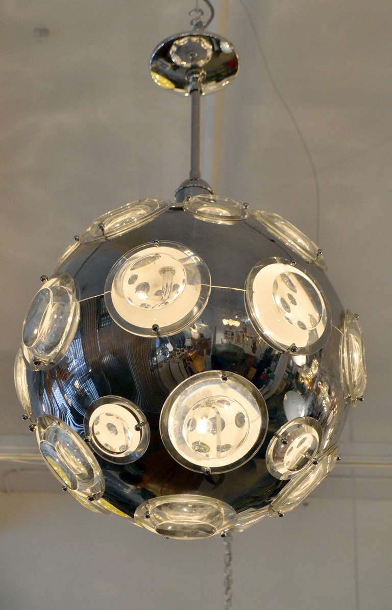 A strikingly futuristic chandelier by Oscar Tolasco, Italy. The chandelier is comprised of a chromed globe with glass lenses that emit and magnify the light. A wonderful and forward thinking design from the 1960's.