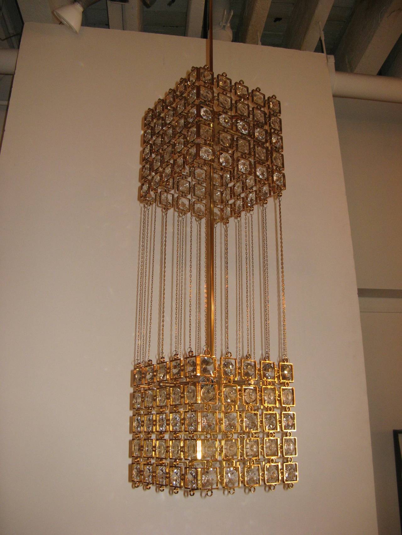 Two-tier gilded metal pendant or chandelier with insets of Austrian crystals. The square shades are connected with very fine chains, Austria, circa 1960.
Newly electrified with eight candelabra sockets.