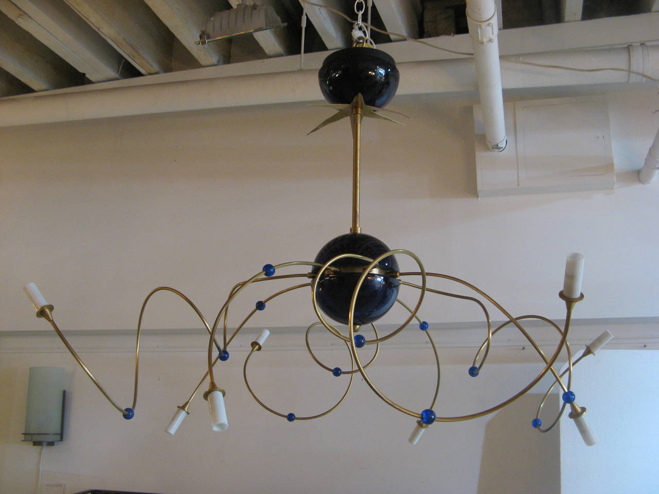 Italian chandelier with eight spiraling brass arms with spherical blue glass beads and white glass diffusers. The arms are issued from a central sphere in blue glass suspended from a single stem with a brass star element and canopy, Murano, Italy,