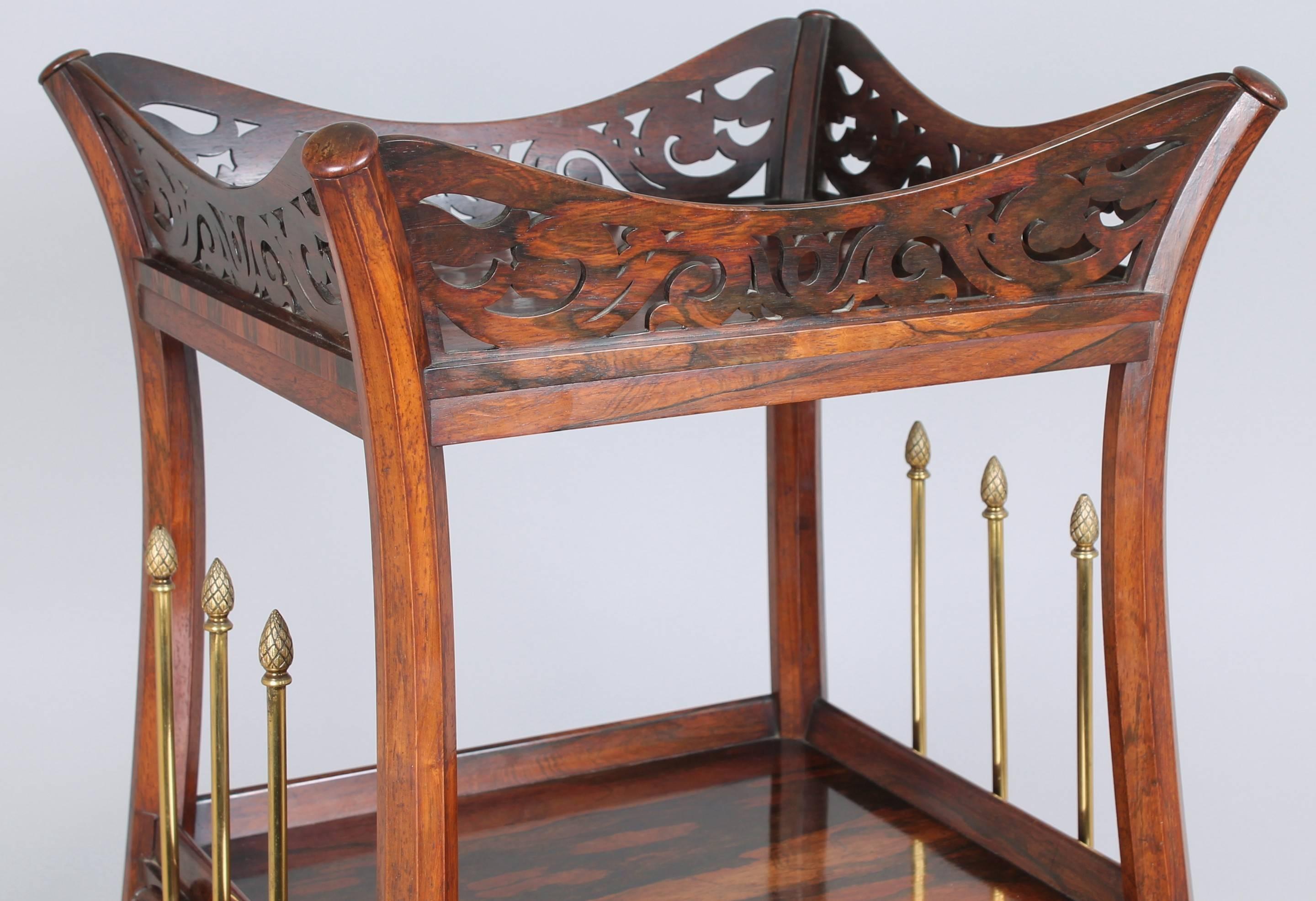 A fine and unusual Regency rosewood whatnot of stylised lyre form, the shelves mounted on boldly-curved supports, surmounted by an angled openwork gallery, the sides with triple gilt-brass vertical rods headed by pine cones. The base fitted with a