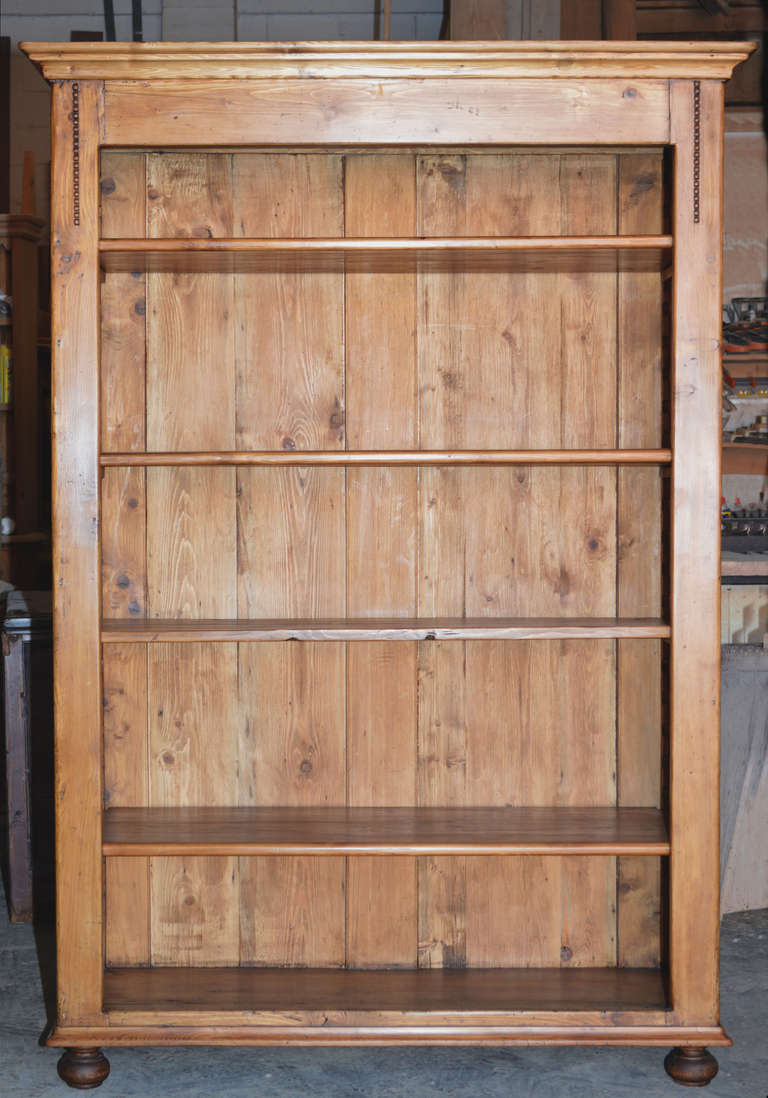 Bookcase with five fully adjustable shelves. Decorative hand-carved beading in upper corners. 
Note the system for adjusting shelves and the beveled, floating panels that make up the back. Walls are joined to top and bottom with hand-cut