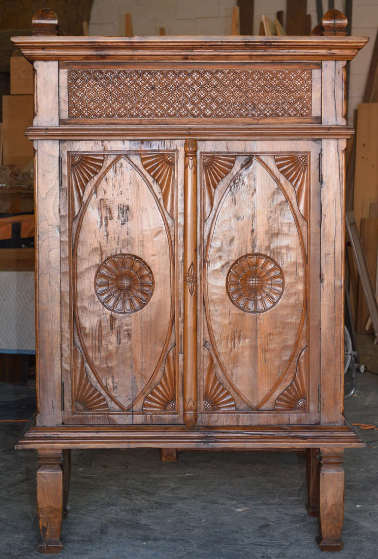 Heavily carved teakwood cabinet with traditional sunburst design.
