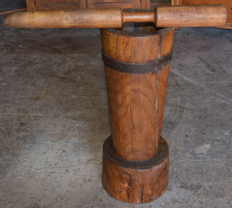 Large wooden mortar and pestle with wrought iron strap. This mortar was used for grinding grain and hemp seed. It was carved from a single piece of wood. The strap was added early to keep the mortar from cracking. Some cracks are visible but will