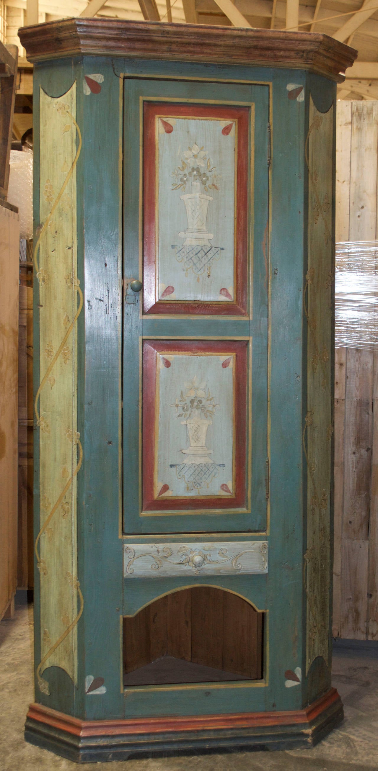 Masterfully painted corner cabinet with two doors, a drawer and a cubby-hole below. 