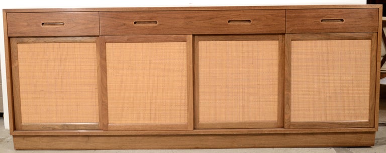 Classic Edward Wormley design for Dunbar, with the relatively uncommon accent of caned sliding doors on the bottom compartments. Thin drawers fill both side cabinets, central compartment has an adjustable shelf. Excellent original finish.